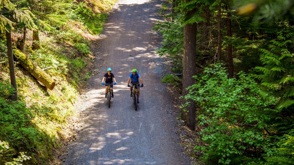 Two mountain bikers riding on a gravel trail around Lost Lake in Whistler, BC