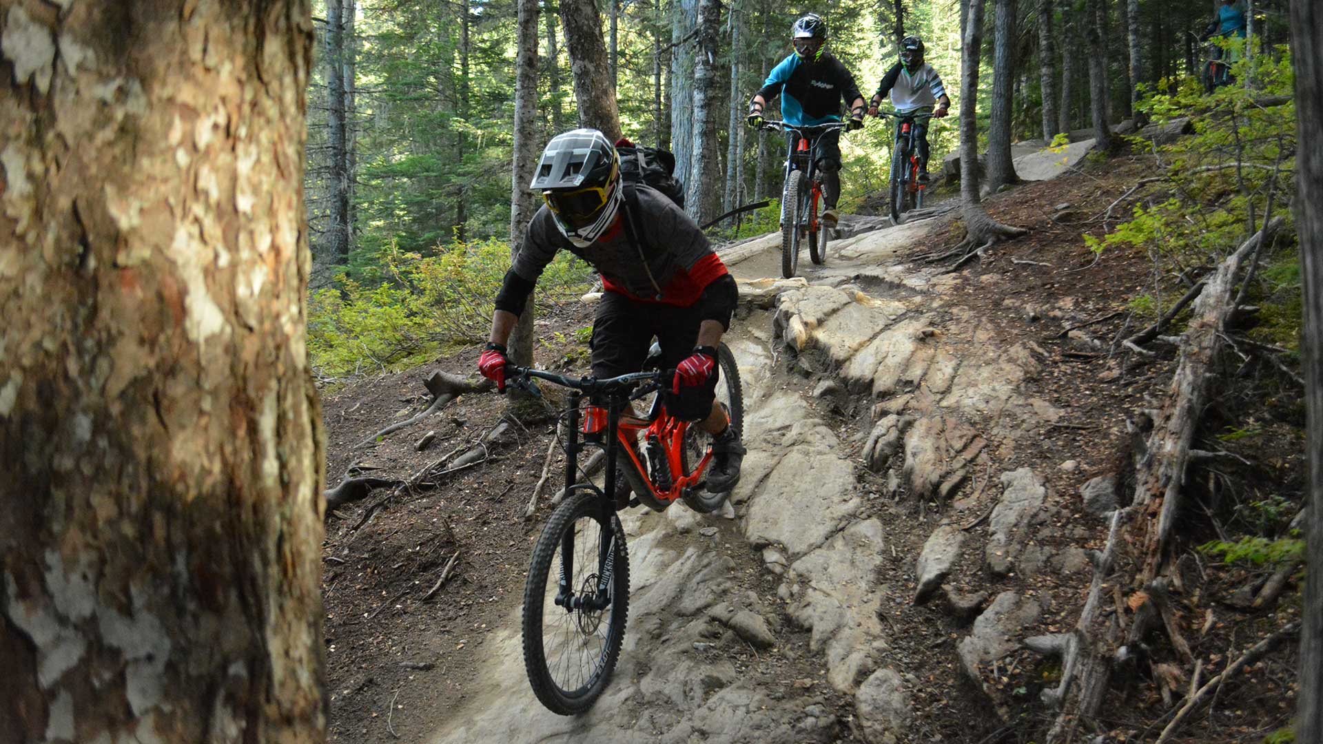 Bike guide taking guests down a rocky trail in the Whistler Mountain Bike Park