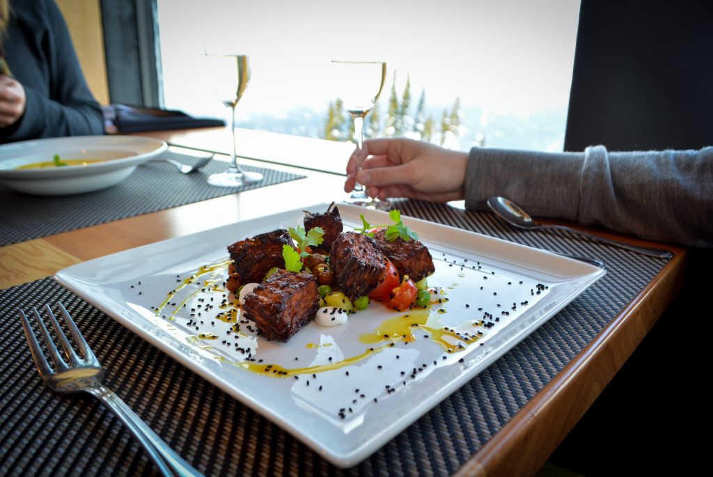 Plate of food and champagne glasses while dining on top of Blackcomb Mountain at Christines Fine Dining Restaurant