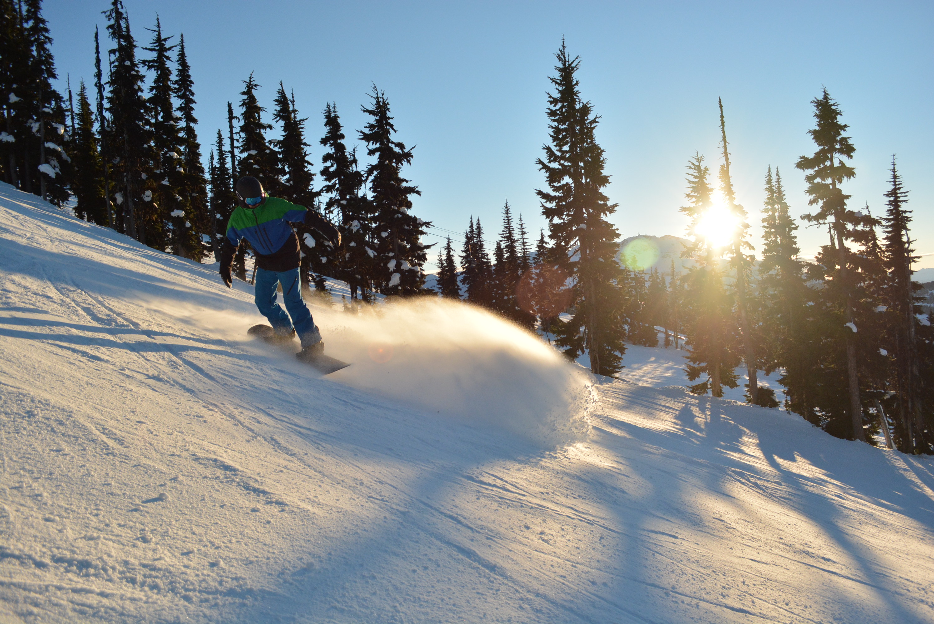 snowboarding riding down whistler mountain at sunset