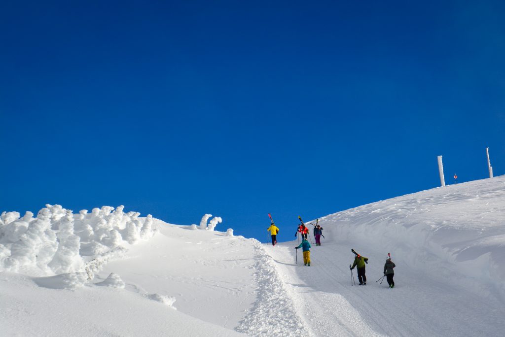 Skiers and snowboarders walking up Flute Bowl on Whistler Mountain